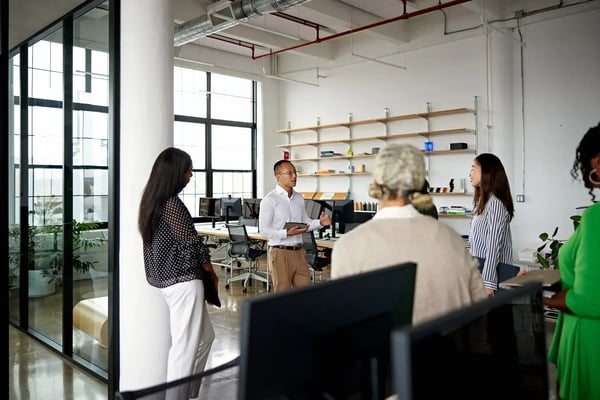 Na imagem, um grupo multiénico formado por pessoas jovens e de meia idade estão conversando em uma sala de uma empresa. O tema do texto é avenidas de crescimento, o que são e as oportunidades na área.