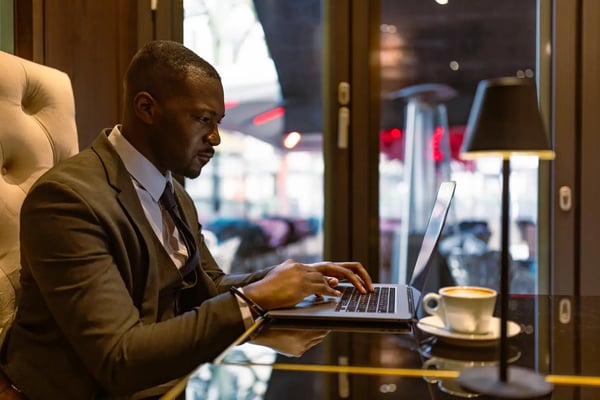 Profissional de meia idade negro e vestindo terno está em frente a uma mesa com um notebook, onde digita algo. Ele está focado se envolve em trabalho remoto. O texto trata sobre o conceito de private equity.