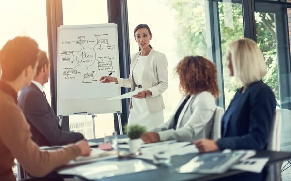 A imagem traz um grupo de pessoas em uma sala de reuniões, apresentando uma reunião de negócios. O texto trata sobre a premiação Selo Cubo.