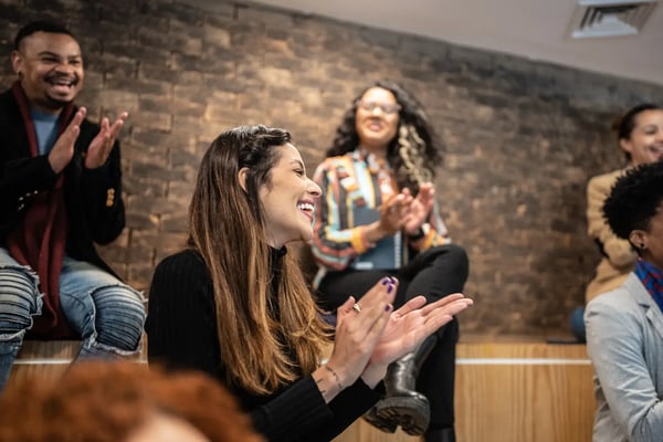 A imagem apresenta um grupo de pessoas batendo palmas em um seminário. O texto trata sobre a metodologia de squads.