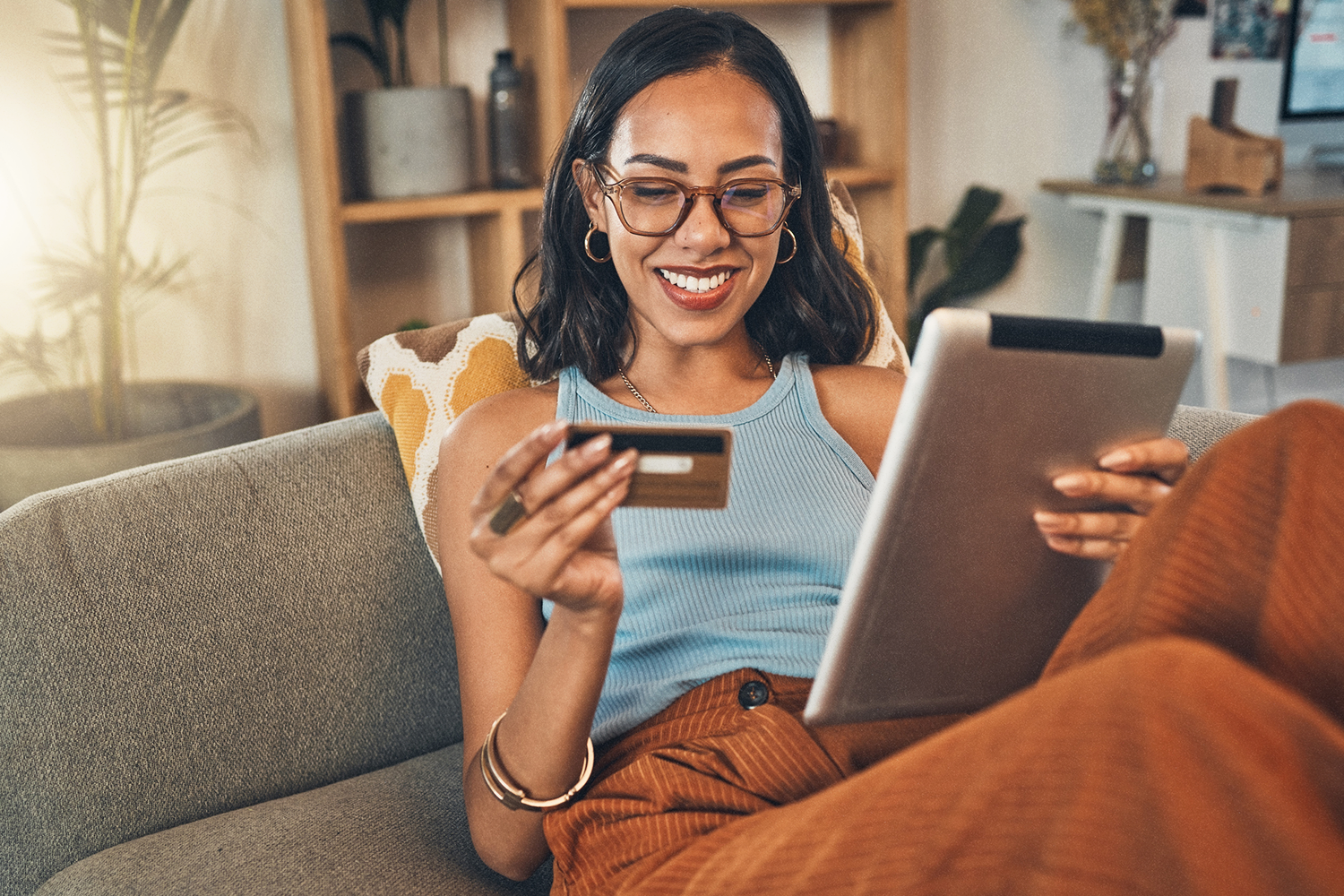 Imagem de uma mulher realizando uma compra online, com o cartão na mão